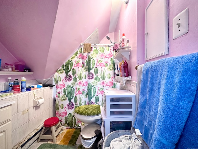 bathroom with toilet, tile walls, and vaulted ceiling