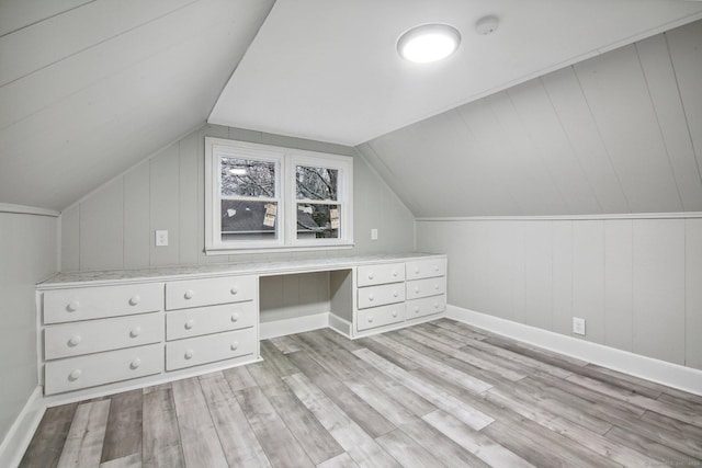 additional living space featuring wood walls, vaulted ceiling, and light wood-type flooring