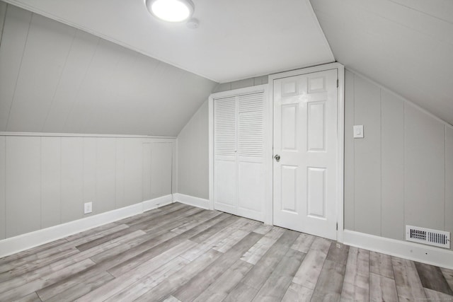 additional living space with light hardwood / wood-style floors and vaulted ceiling