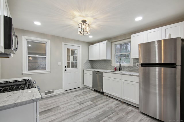 kitchen with white cabinetry, sink, stainless steel appliances, and light wood-type flooring