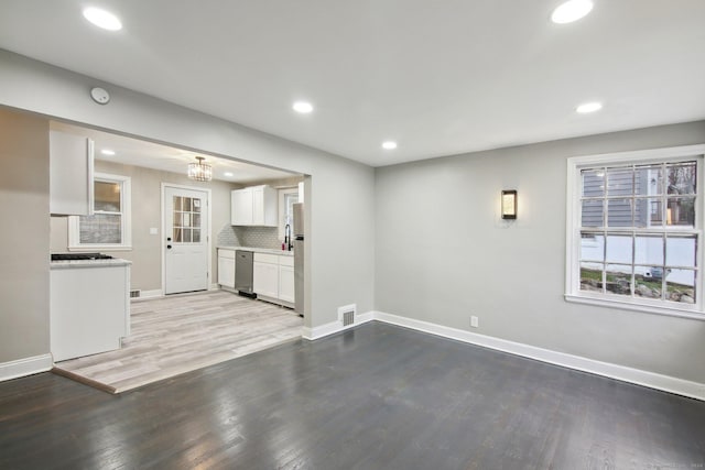 unfurnished living room featuring a notable chandelier and light hardwood / wood-style flooring