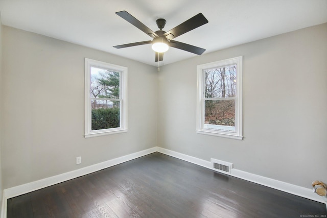 empty room featuring dark hardwood / wood-style flooring, ceiling fan, and plenty of natural light