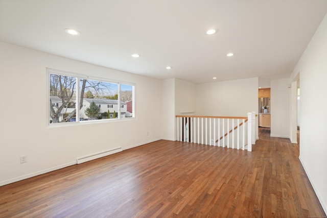 unfurnished room with baseboard heating and dark wood-type flooring