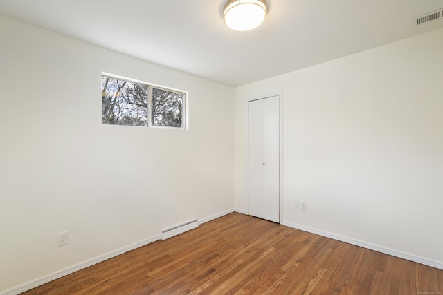 spare room with wood-type flooring and baseboard heating