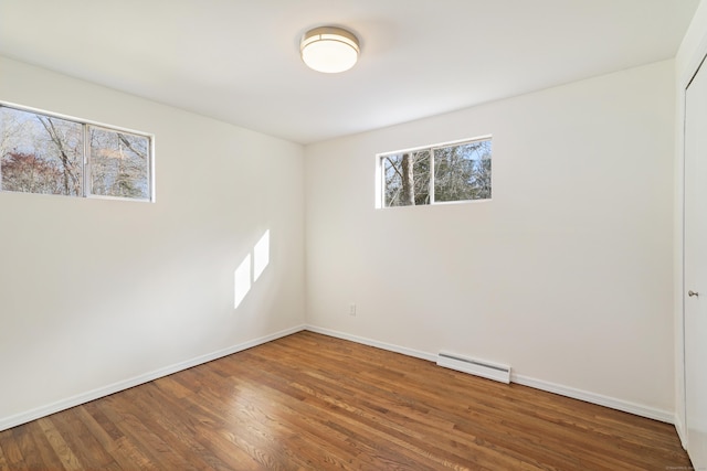 unfurnished room with hardwood / wood-style floors and baseboard heating