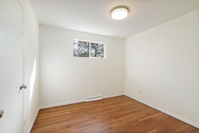 spare room with wood-type flooring and a baseboard heating unit