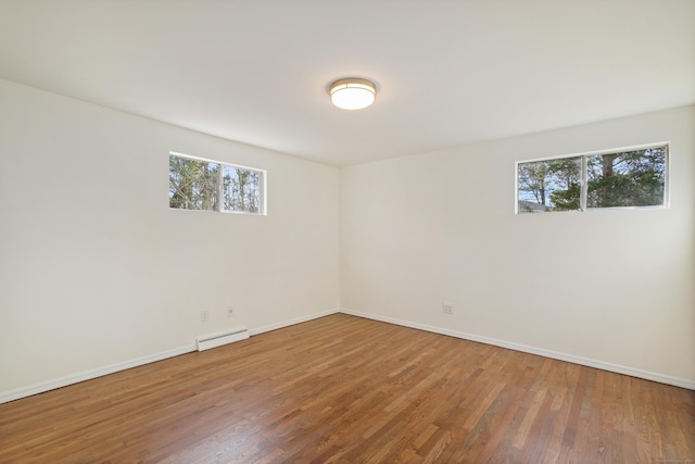 empty room with hardwood / wood-style floors and a baseboard radiator