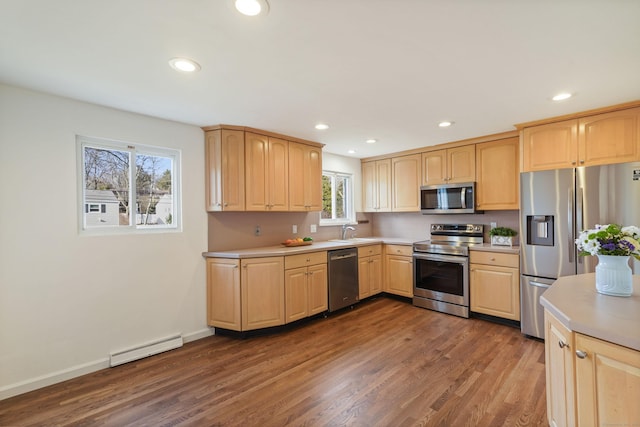 kitchen featuring appliances with stainless steel finishes, dark hardwood / wood-style floors, baseboard heating, and a healthy amount of sunlight