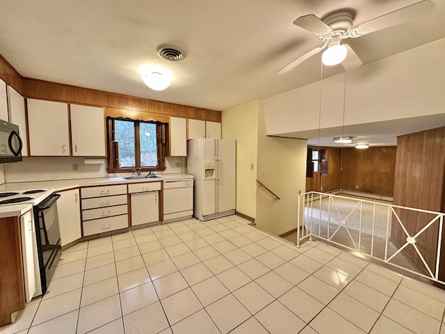 kitchen with white appliances, sink, wooden walls, ceiling fan, and white cabinetry