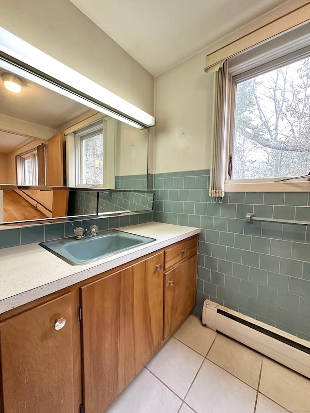 kitchen with light tile patterned flooring, tile walls, sink, and a baseboard heating unit