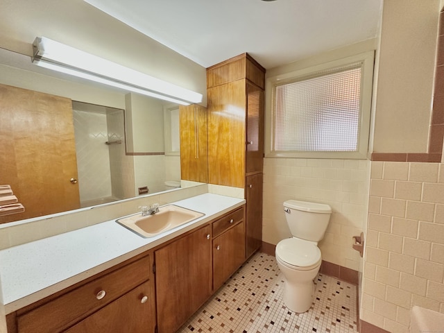 bathroom featuring tile patterned floors, vanity, toilet, and tile walls