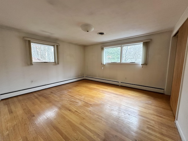 interior space featuring light wood-type flooring, baseboard heating, and multiple windows