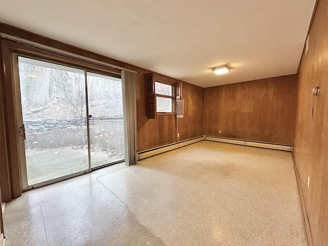 empty room with a baseboard heating unit and wood walls