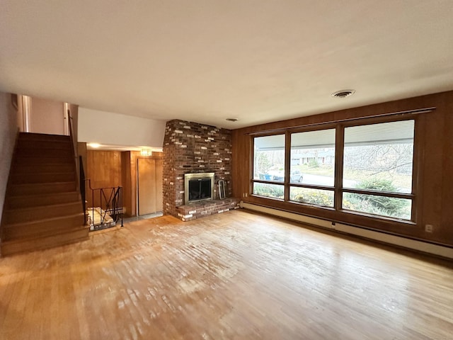 unfurnished living room featuring a fireplace, a baseboard radiator, and light hardwood / wood-style flooring