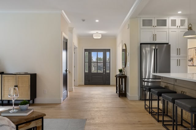 interior space featuring high end refrigerator, crown molding, pendant lighting, white cabinets, and light hardwood / wood-style floors