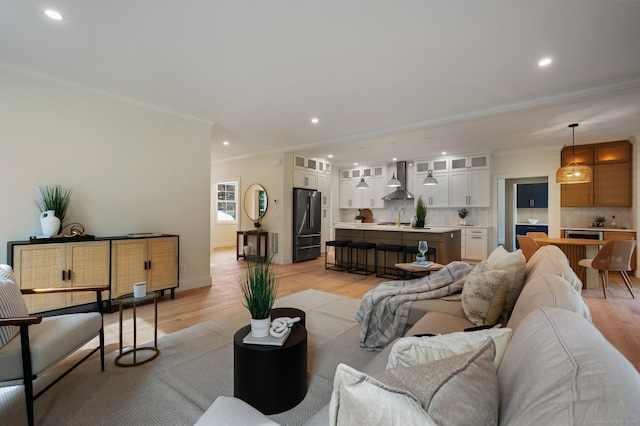 living room with light hardwood / wood-style floors, sink, and crown molding