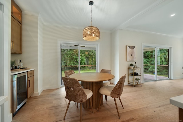 dining room featuring a wealth of natural light, light wood-type flooring, crown molding, and wine cooler