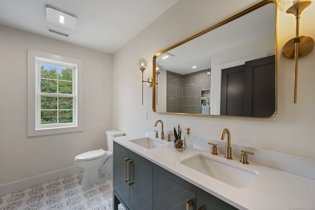 bathroom featuring tile patterned flooring, vanity, toilet, and tiled shower