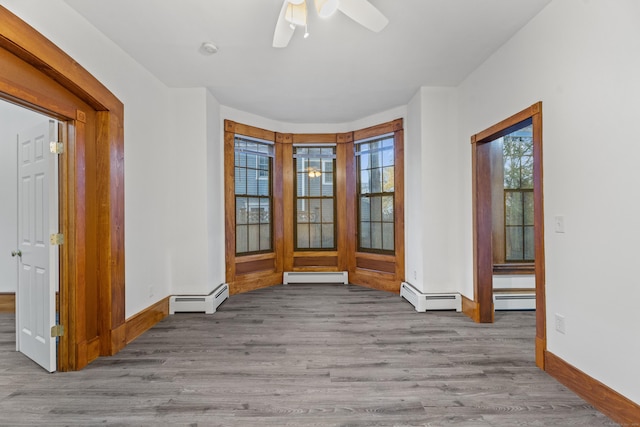 empty room featuring a baseboard radiator, light hardwood / wood-style flooring, and ceiling fan