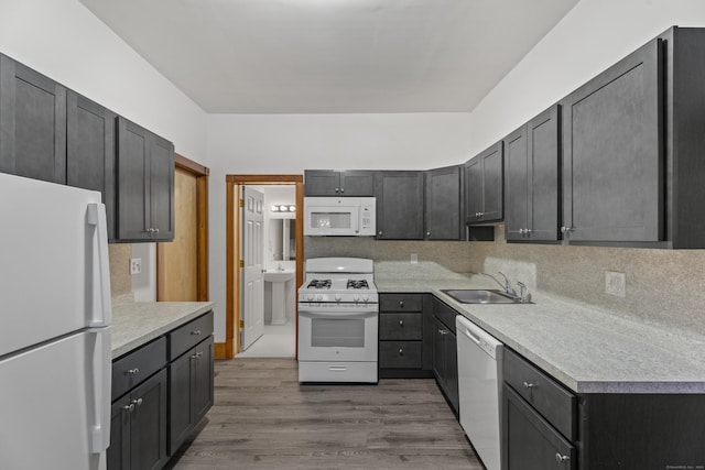 kitchen with decorative backsplash, sink, wood-type flooring, and white appliances