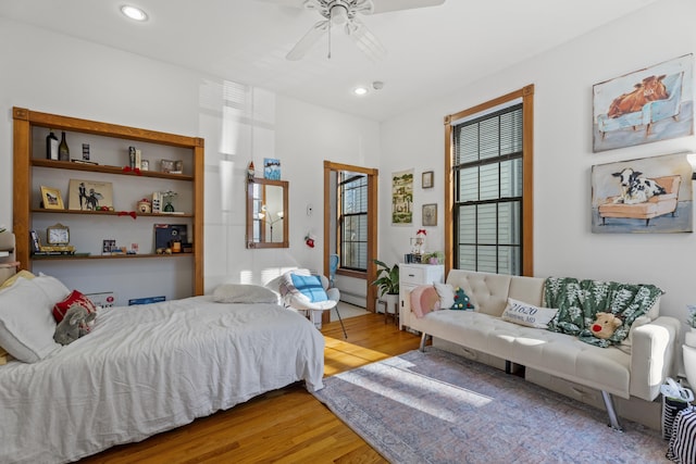 bedroom with ceiling fan, light hardwood / wood-style flooring, and a baseboard heating unit