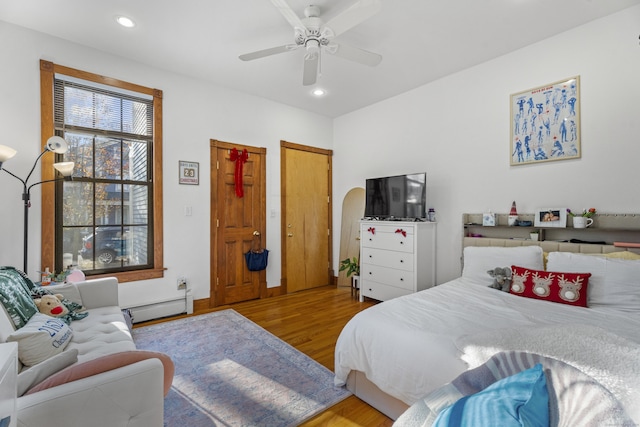 bedroom with baseboard heating, light hardwood / wood-style flooring, and ceiling fan