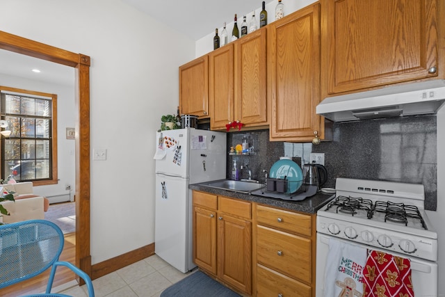 kitchen featuring backsplash, white appliances, a baseboard heating unit, sink, and light tile patterned floors