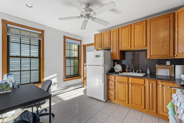 kitchen with ceiling fan, sink, baseboard heating, dark stone countertops, and white appliances