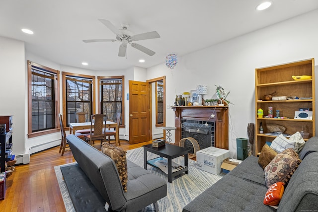 living room featuring baseboard heating, ceiling fan, and hardwood / wood-style flooring