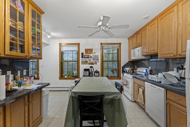 kitchen featuring backsplash, dark stone countertops, a baseboard radiator, and white appliances