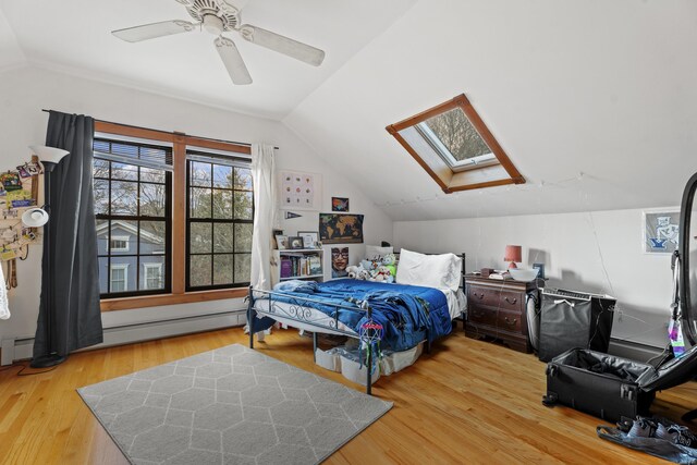 bedroom with hardwood / wood-style flooring, ceiling fan, lofted ceiling with skylight, and a baseboard radiator