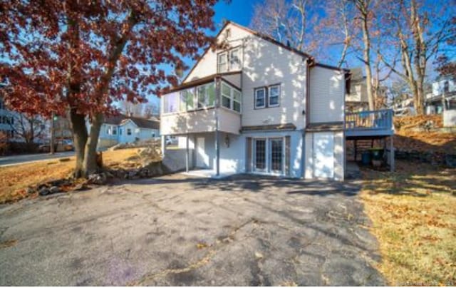 back of property with a deck and a sunroom