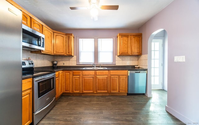 kitchen featuring sink, decorative backsplash, ceiling fan, appliances with stainless steel finishes, and dark hardwood / wood-style flooring