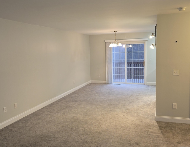 carpeted spare room with a notable chandelier