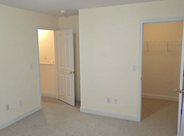 unfurnished bedroom featuring light carpet and a spacious closet