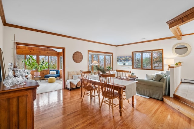 dining area with ornamental molding, baseboard heating, and light wood-type flooring