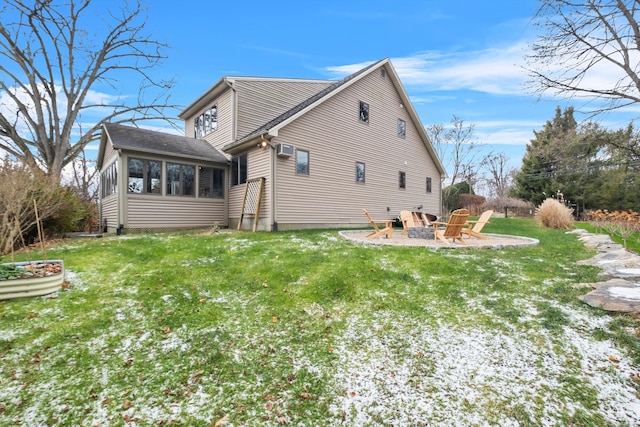 rear view of property featuring a sunroom, a yard, a patio, and a fire pit