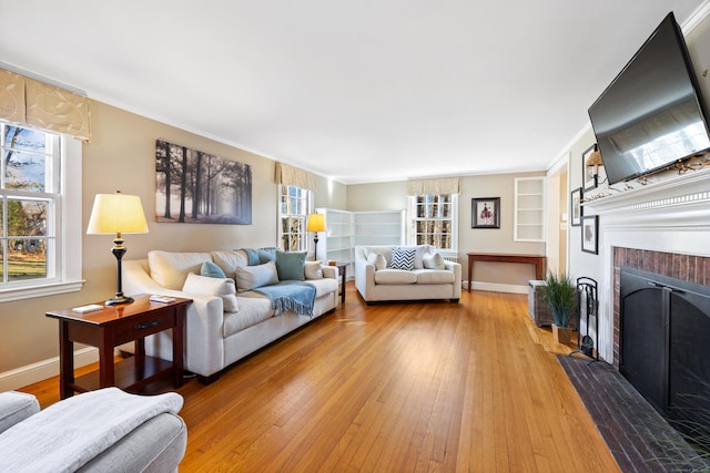 living room with crown molding, wood-type flooring, and a brick fireplace