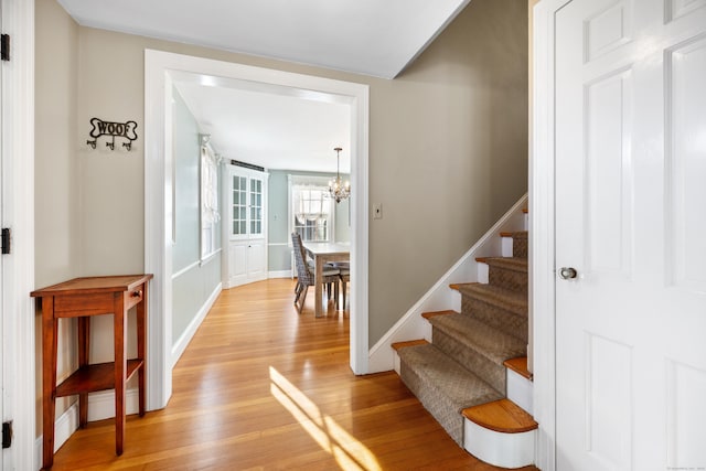 staircase with hardwood / wood-style flooring and a chandelier