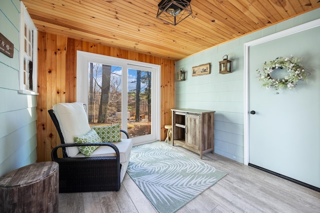 sitting room featuring wooden walls, light hardwood / wood-style flooring, and wooden ceiling