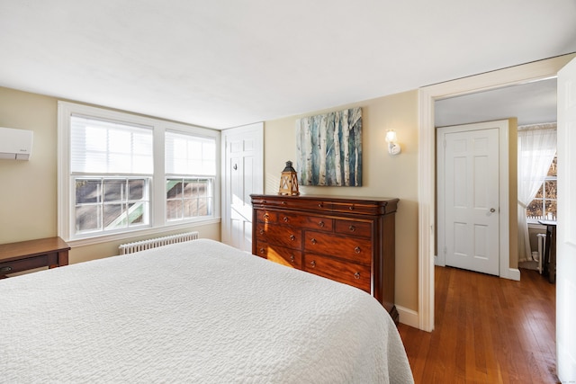 bedroom featuring a wall unit AC, wood-type flooring, and radiator