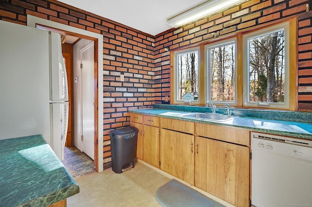 kitchen with white appliances, sink, and brick wall