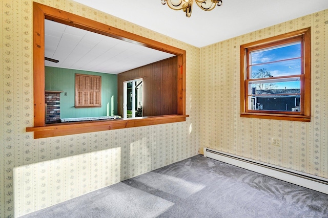 carpeted spare room featuring a chandelier and baseboard heating