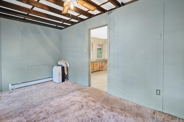 carpeted empty room featuring a baseboard heating unit