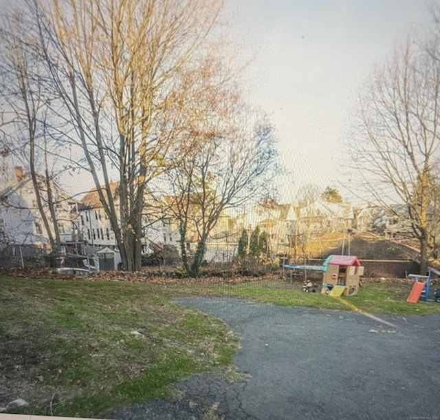 view of home's community with a playground, a yard, and a trampoline