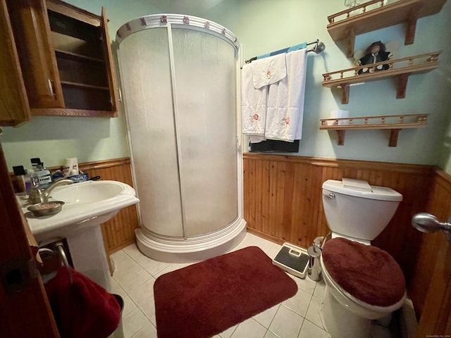 bathroom featuring tile patterned flooring, wooden walls, toilet, and a shower with shower door