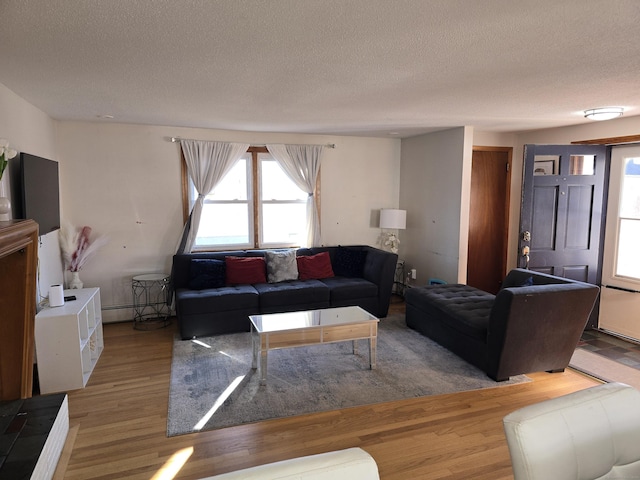 living room featuring wood-type flooring, a textured ceiling, and a baseboard heating unit