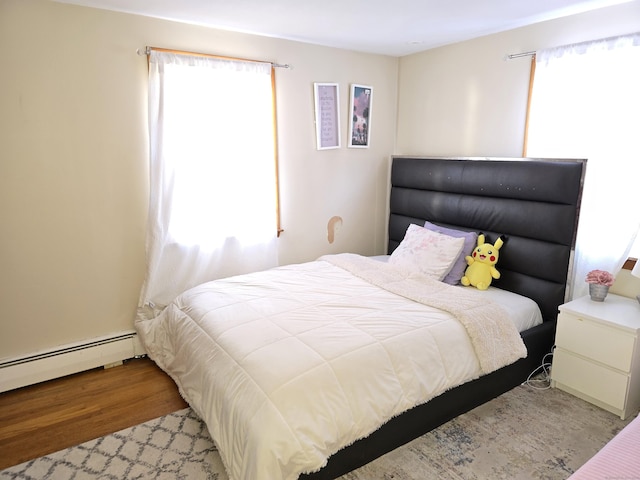 bedroom featuring light wood-type flooring and a baseboard heating unit