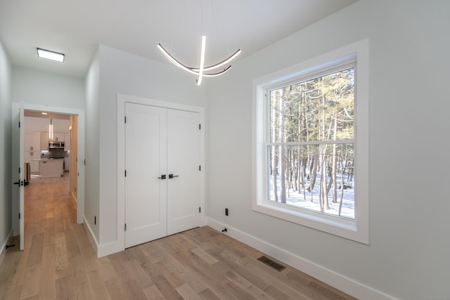 interior space featuring visible vents, light wood-style flooring, and baseboards