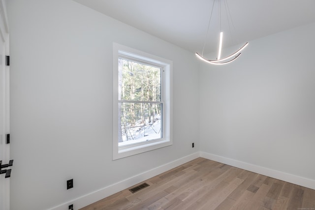 empty room featuring visible vents, light wood-style flooring, and baseboards